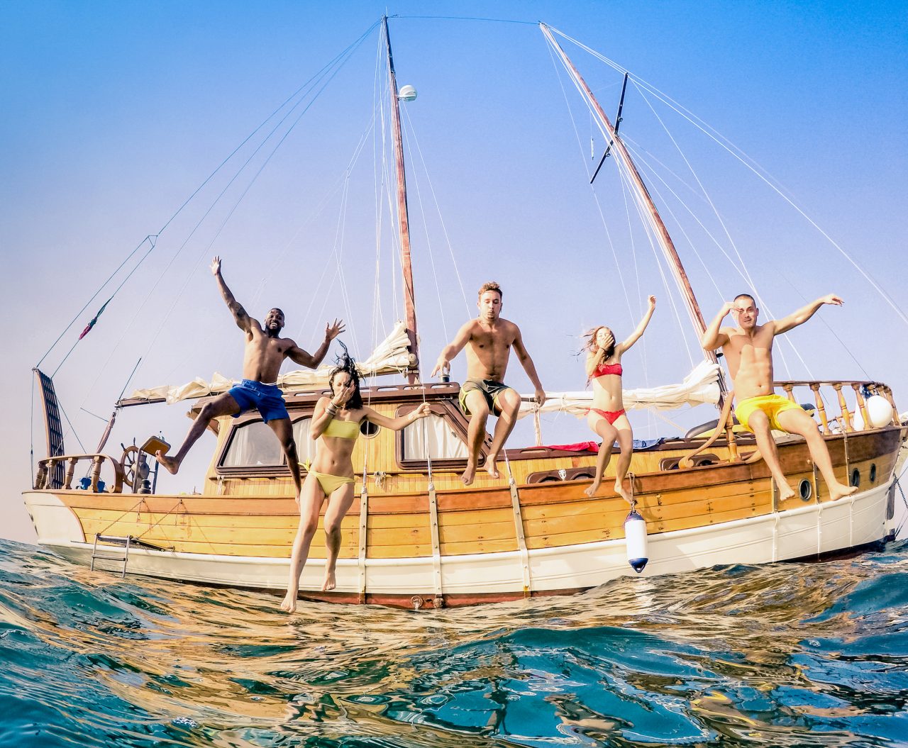 Frontal view of young multiracial friends jumping from wooden sa