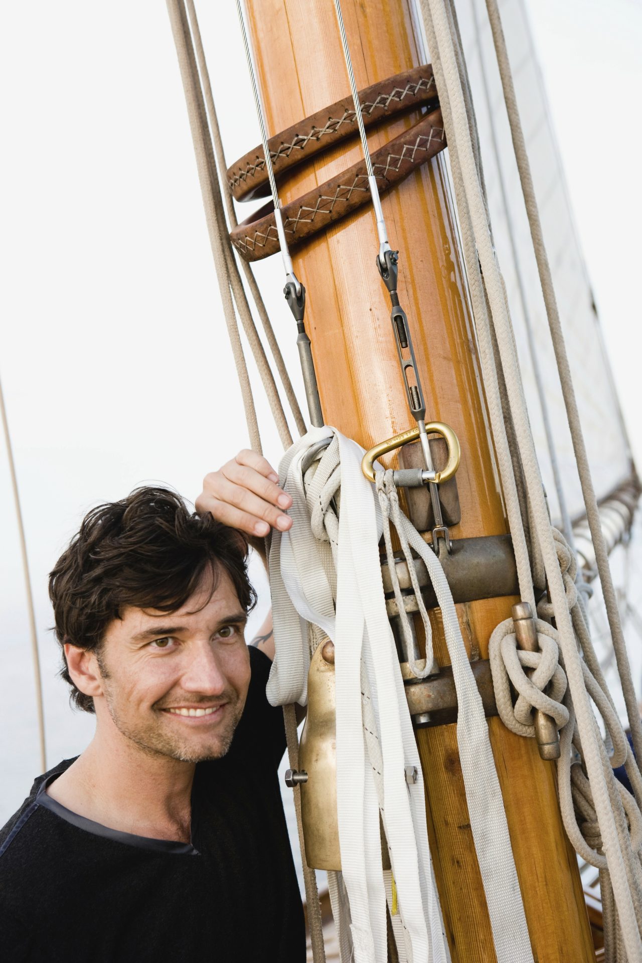 man sitting on deck of sailing boat